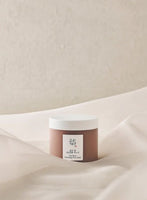Matte brown jar with white lid of pore-cleansing mask set against soft beige fabric background