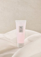 Soft pink tube of hydrating water gel with minimalistic label placed on flowing cream fabric background