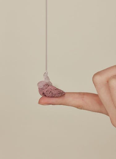 Light pink water gel dripping onto a finger atop a smooth creamy textured swatch on beige background