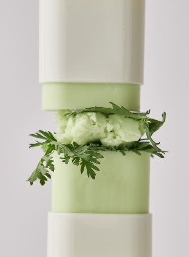 Light green sun stick with creamy texture and fresh mugwort leaves highlighting strong protection benefit
