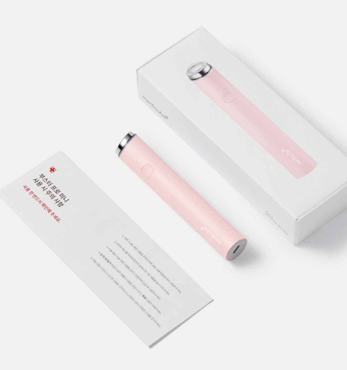 medicube AGE-R Booster Pro "MINI" #White pink device next to white packaging and instruction leaflet on white surface