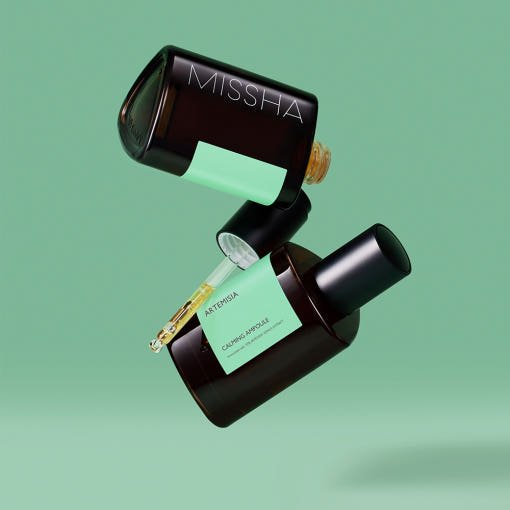 Two dark amber ampoule bottles with mint green labels and dropper caps on a soft green background