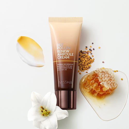 Tube of nourishing ampoule cream with bee pollen granules, honeycomb piece, floral accents, and cream swatches on white background
