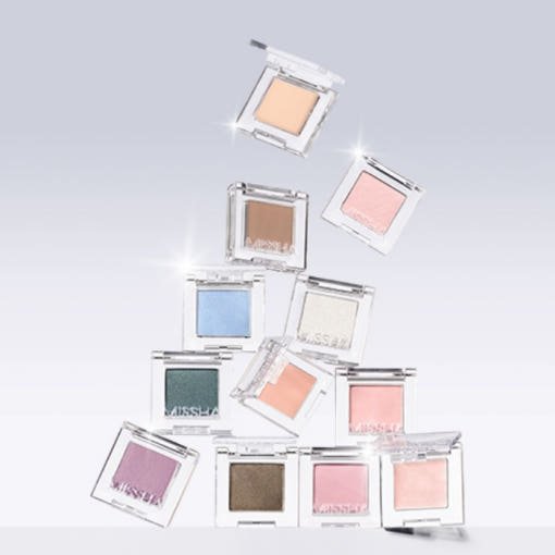 Various ultra-pigmented eyeshadows in soft pastel and neutral shades in clear square compacts on light background