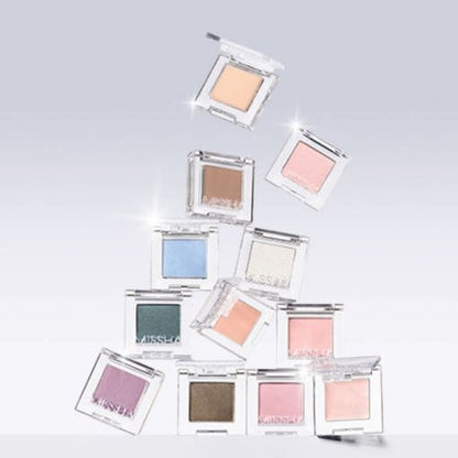 Assorted ultra-pigmented eyeshadows in clear cases in soft pastel and neutral shades on pale gradient background