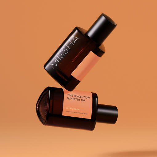 Two amber glass serum bottles with black caps labeled for anti-aging lifting serum on a warm beige background