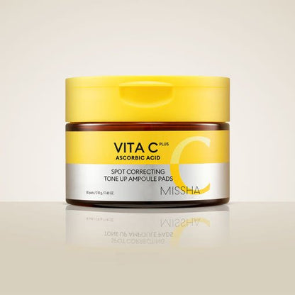Amber jar with bright yellow lid containing brightening spot correcting ampoule pads on beige surface