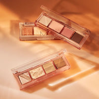 Three compact eyeshadow palettes with versatile neutral and warm shades in transparent cases on warm beige surface