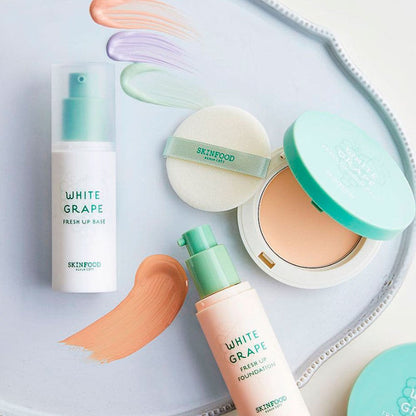 Foundation bottle and compact with mint-green accents surrounded by color-correcting cream swatches on white tray