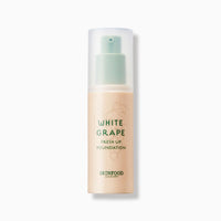 Matte beige foundation bottle with mint green pump and subtle grape illustration on white background