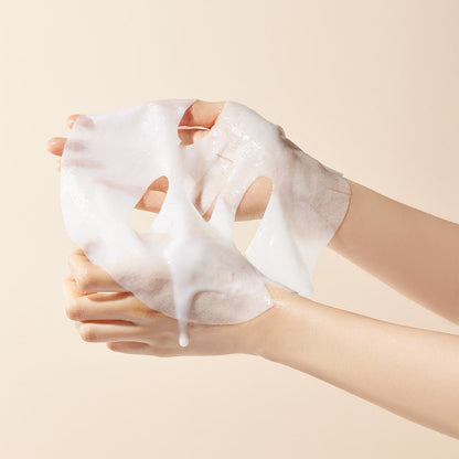 Hands holding a moist, translucent sheet mask with a creamy texture against a soft beige background