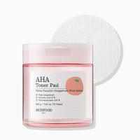 Clear jar of gentle exfoliating toner pads with pink grapefruit extract and textured cotton pad on white background