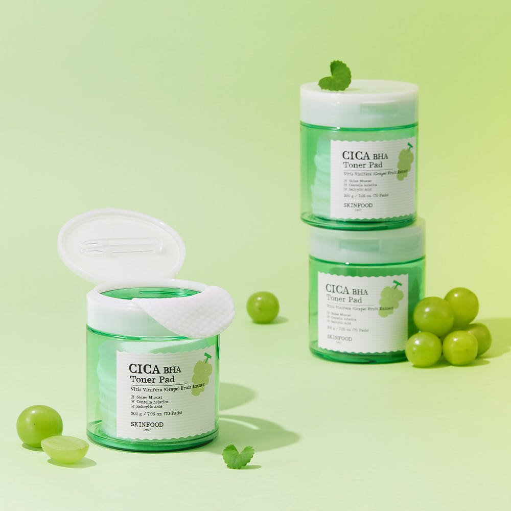 Green clear jars of toner pads stacked and open with fresh muscat grapes and mint leaves on light green background