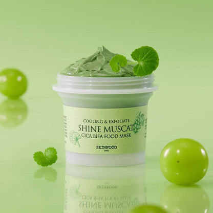 Open jar of cooling green food mask with creamy texture and fresh leaves on light green background for deep cleansing