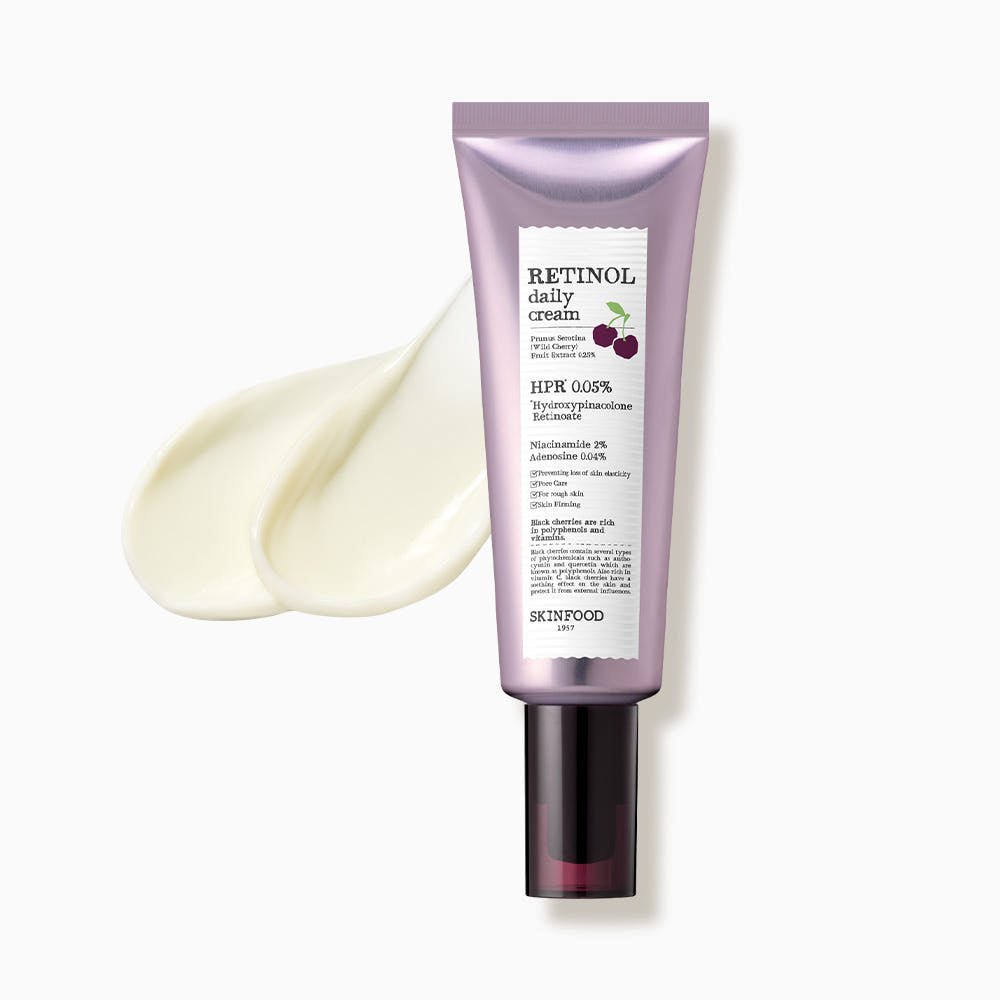 Lavender-toned tube of retinol daily cream with black pump beside creamy white lotion swatches on white background