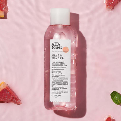 Clear pink toner bottle with white label highlighting exfoliating acids on a soft pink background with grapefruit pieces