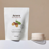 Refill pack of peptide pore tightening pads with natural acorn design next to stacked cotton pads in a clear container
