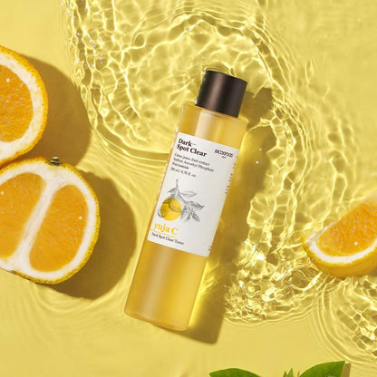 Clear toner bottle with citrus fruit slices on yellow background highlighting brightening benefits
