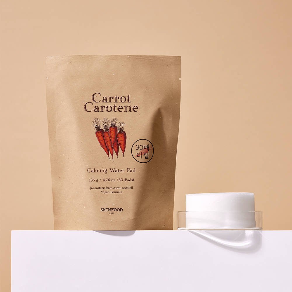 Natural beige pouch of calming water pads with carrot illustration beside a clear container holding round white pads