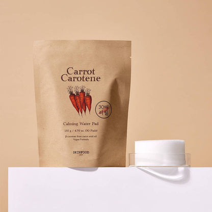 Natural beige pouch of calming water pads with carrot illustration beside a clear container holding round white pads