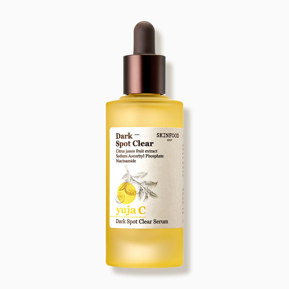 Frosted yellow serum bottle with brown dropper cap and label highlighting brightening ingredients for dark spot care