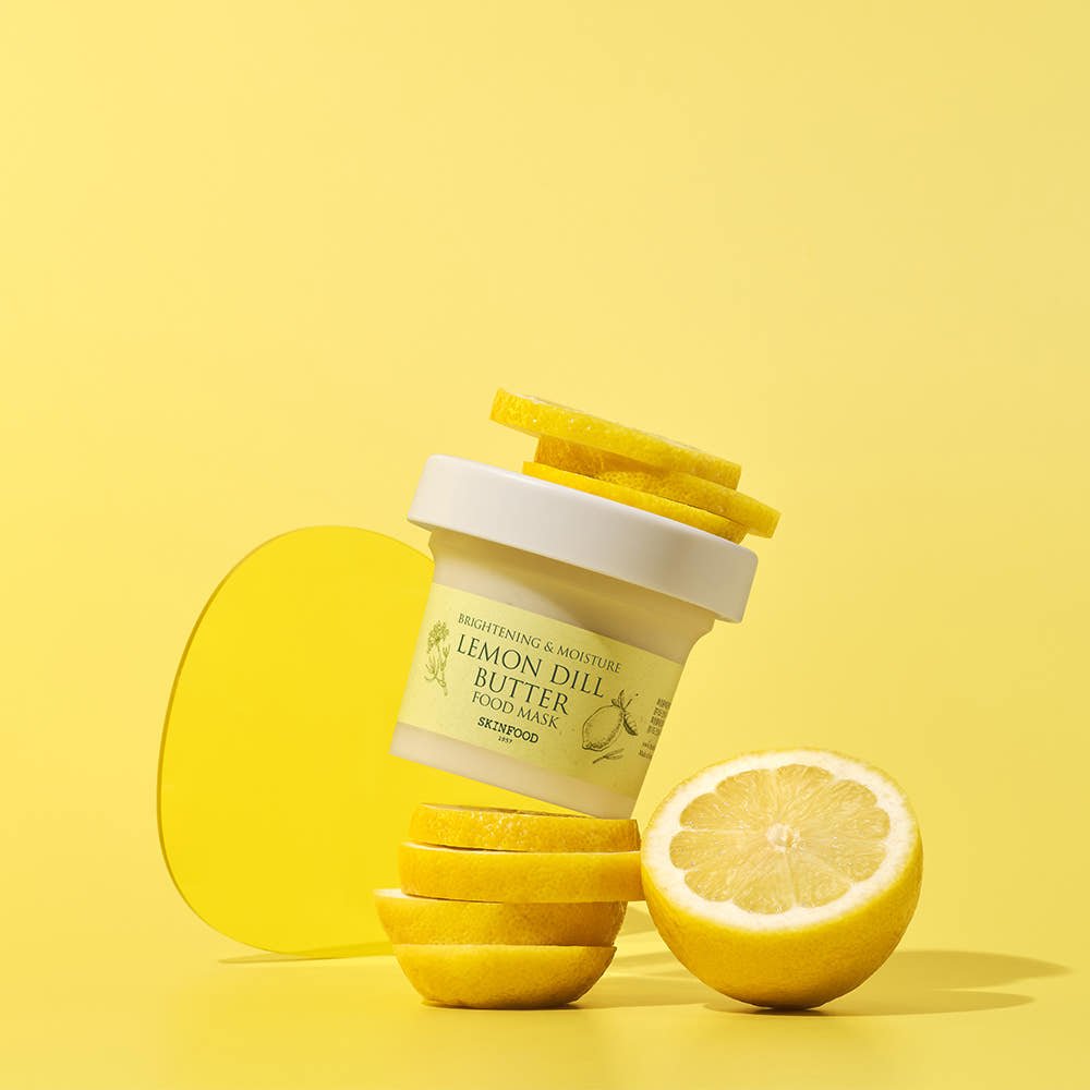 Moisturizing lemon butter food mask jar balanced on sliced lemons with bright yellow background and round yellow shape.