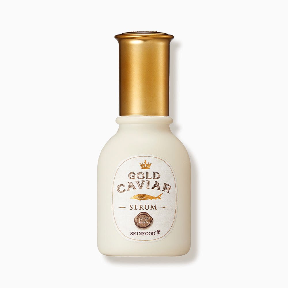 Frosted glass bottle with gold cap containing firming skincare serum labeled Gold Caviar EX Serum by SKINFOOD