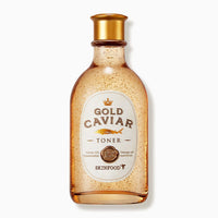 Transparent amber bottle of firming toner with gold flakes and a gold cap on white background