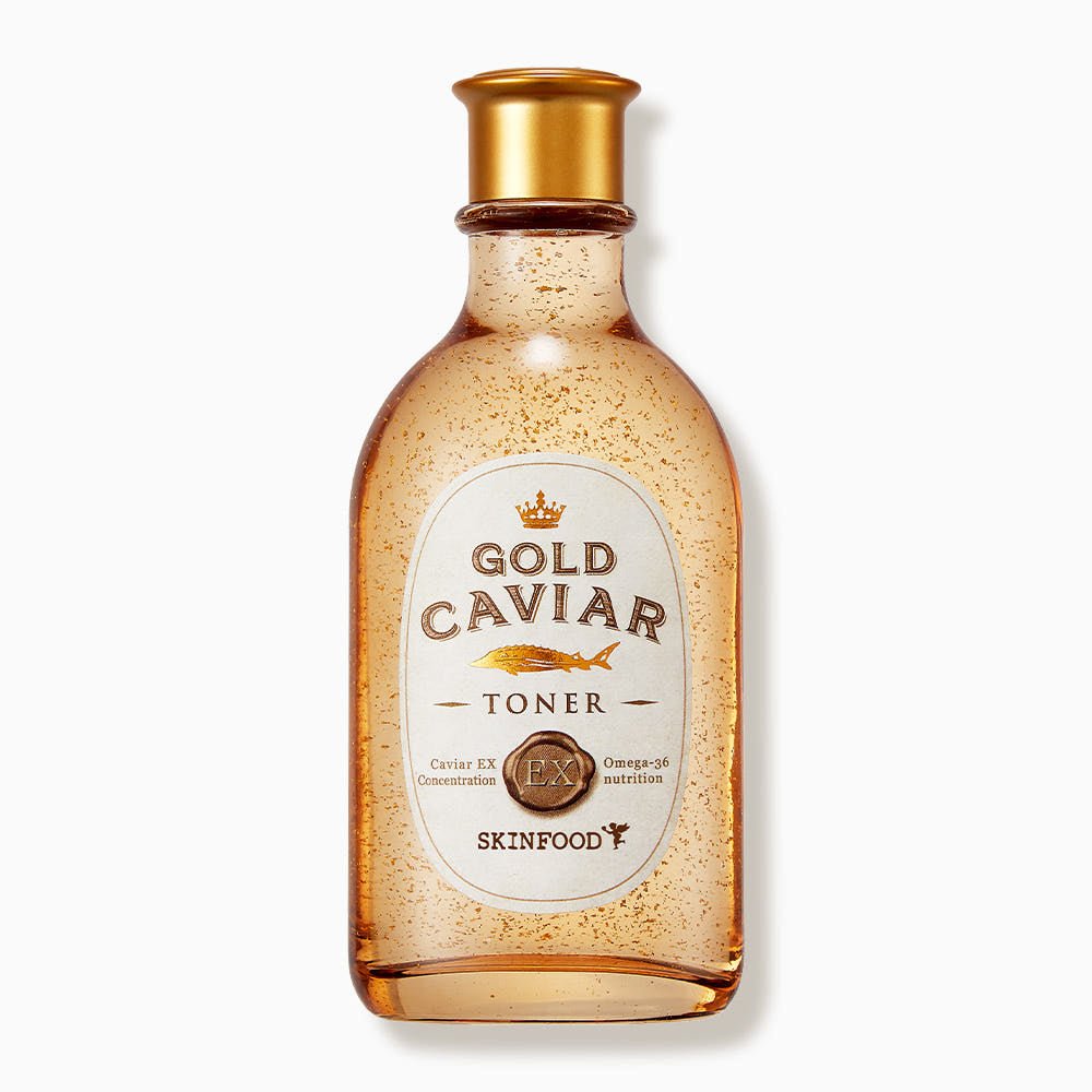Transparent amber bottle of firming toner with gold flakes and a gold cap on white background