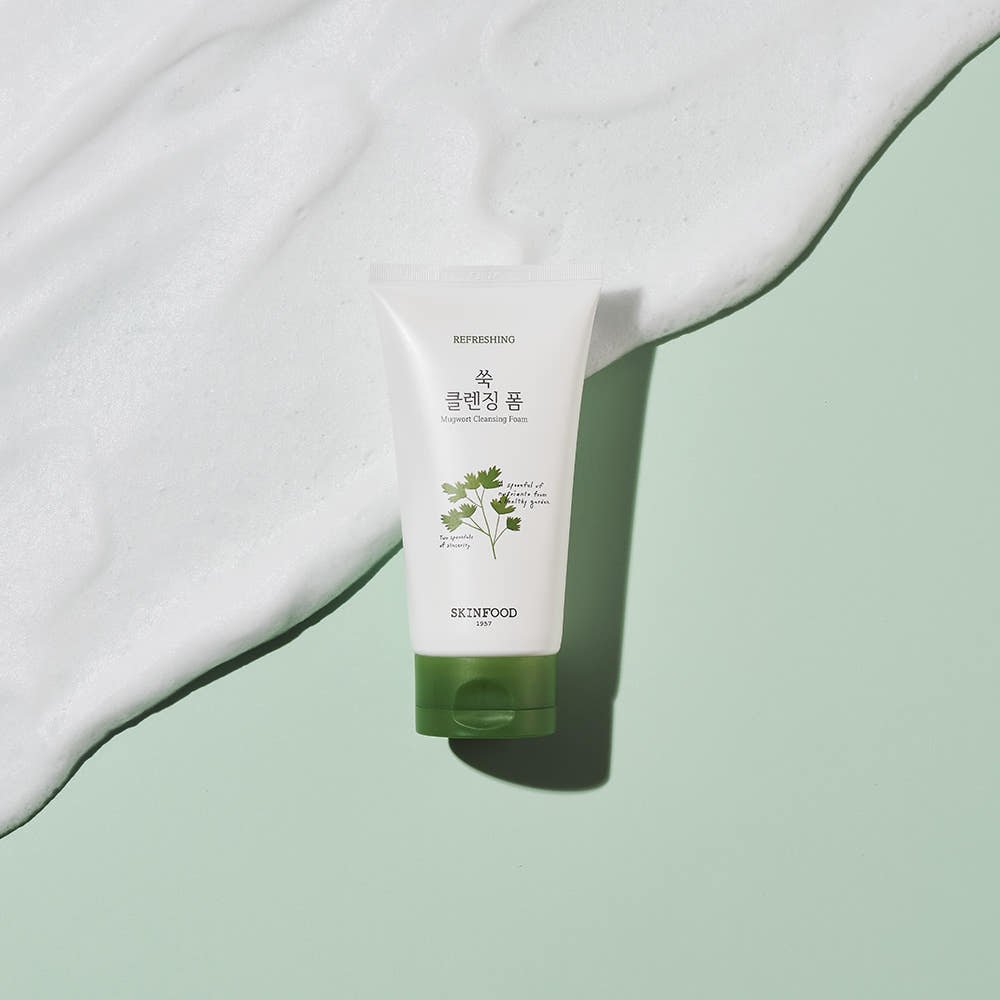 Tube of refreshing cleansing foam with green cap and parsley illustration on soft green background with white foam texture
