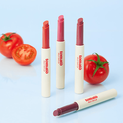 SKINFOOD Tomato Jelly Tint Lip 1.7g in four shades displayed upright and lying down with fresh whole and sliced tomatoes