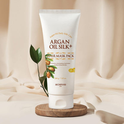 SKINFOOD Argan Oil Silk Plus Hair Mask Pack 200g tube with plant and wooden base showcasing nourishing hair care benefits