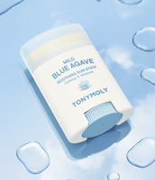 White sun stick container with blue accents labeled Mild Blue Agave Soothing Sun Stick on light blue surface with water droplets