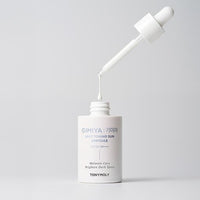 White dropper bottle of sun protection ampoule with a drop about to fall back into the open container on gray background