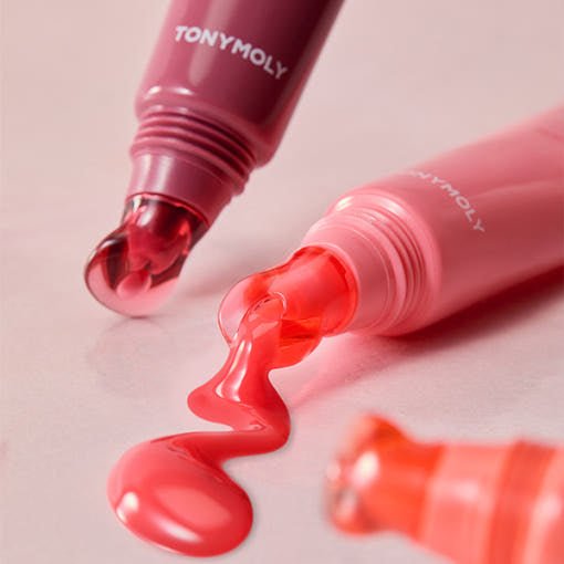 Two pink lip jelly tubes with glossy vibrant color flowing from applicator tips on pale pink surface