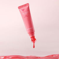 Pink lip jelly tube dispensing vibrant red jelly with a smooth glossy texture over a pale pink background