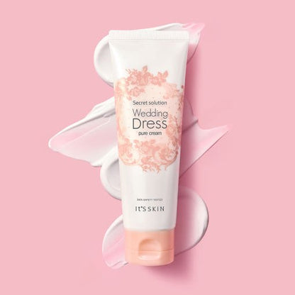Tube of light pink skincare cream with floral details on pink background and swatches of tone-up cream behind it
