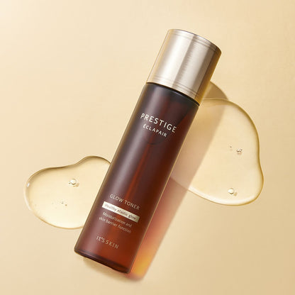 Brown translucent bottle of glow toner with gold cap on beige surface with clear gel drops nearby