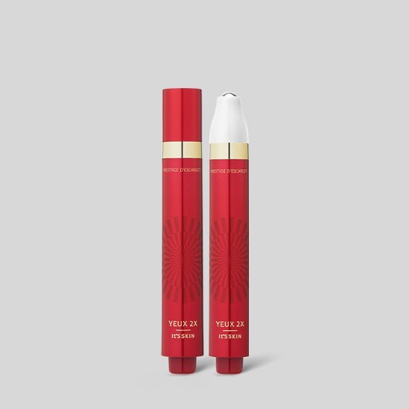 Two slim red skincare tubes with gold accents, one capped and one with white applicator tip, on gray background