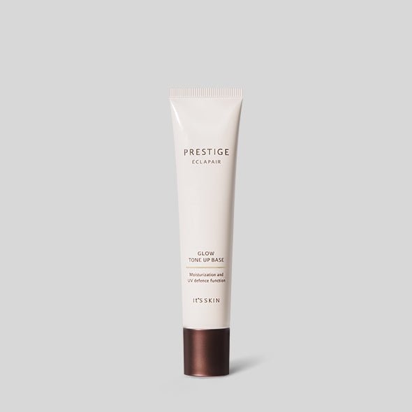 Slim beige tube of glow tone up base with brown cap for even skin tone and UV protection on gray background