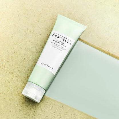 Tube of mild peeling gel with soft green packaging lying on textured beige and smooth blue surfaces