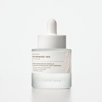 Frosted glass dropper bottle with white label featuring niacinamide 10% brightening serum on plain background