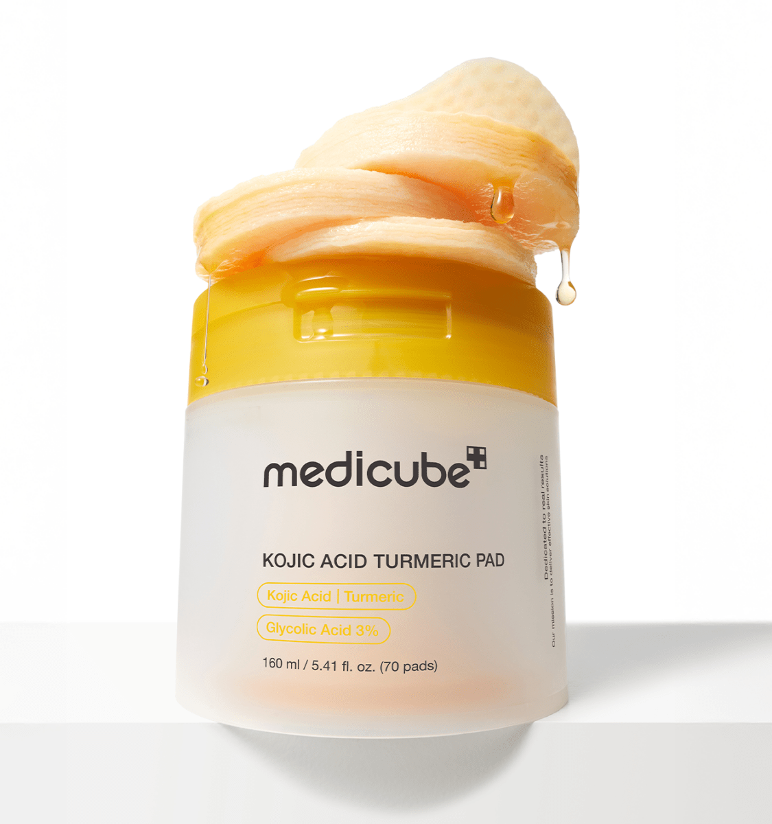 medicube Kojic Acid Turmeric Pad 160ml/70ea in frosted jar with yellow lid and exfoliating pad dripping serum for brightening