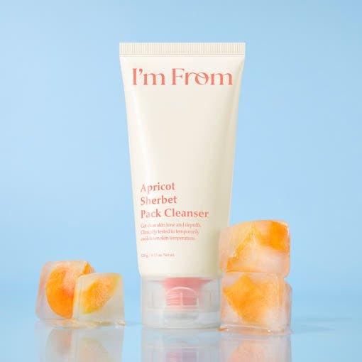 Tube of gentle exfoliating apricot sherbet cleanser with ice cubes on light blue background