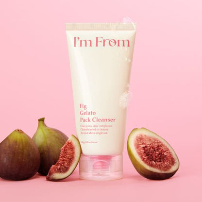 Cream-colored tube of fig gelato cleanser with fresh whole and sliced figs on pink background