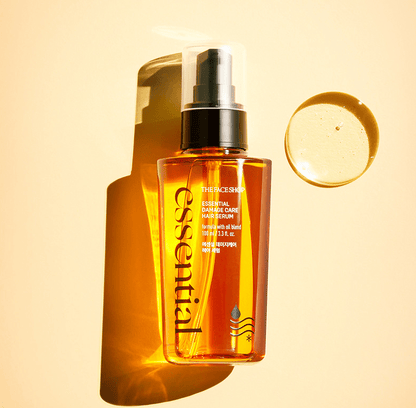 Amber bottle of nourishing hair serum with black pump dispenser casting a long shadow on warm beige background