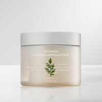 Translucent jar of soothing ampoule pads with simple white lid and minimal green Artemisia leaf design on soft gray background